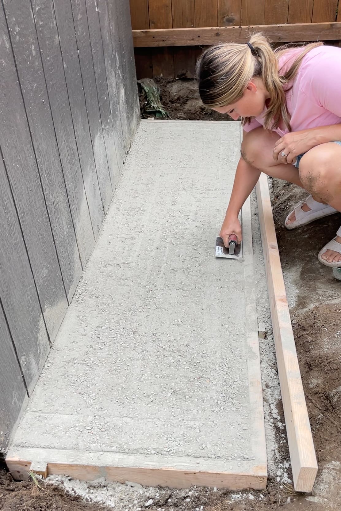 Using a concrete edger tool to round the outside edges of a small dry pour concrete pad